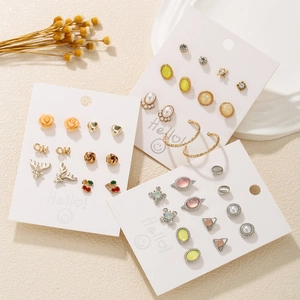 Flat lay of multiple cute stud earring sets including gold roses, hearts and cherry designs