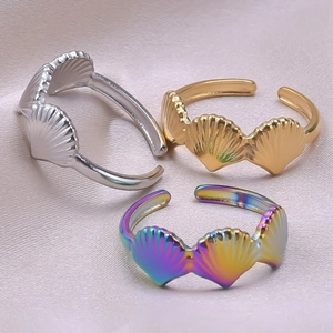 Detail of adjustable fan shell rings in gold, silver, and rainbow on silk fabric
