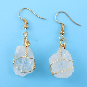 Macro detail of handmade gold wire wrapped clear crystal raw stone hook earrings