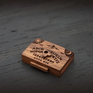 Macro view of a miniature wooden spirit board box with detailed engravings and planchette