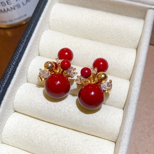 Macro detail of red cluster stud earrings with gold plating and clear zircons in a jewelry box