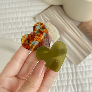 Pair of heart-shaped acetate hair clips in tortoise and olive green colors