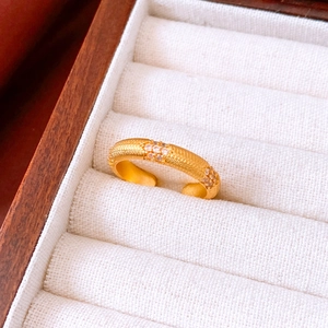 Détail macro d'une bague vintage dorée avec zircons et finition mate en coffret