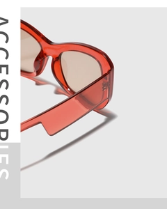 Close-up of modern square sunglasses featuring transparent red frames and light brown lenses