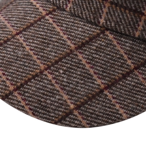 Close-up macro view of the thick brown plaid wool fabric texture of this octagonal beret hat