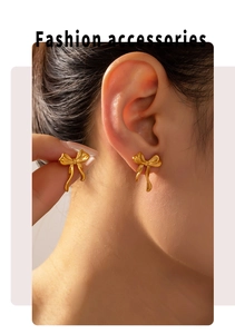 Close-up of golden bow stud earrings worn by a model showing 18k gold plating luster