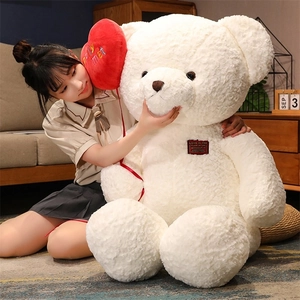 Close-up of a large white teddy bear with a red heart balloon and a soft plush texture