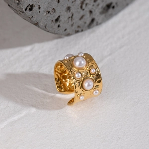 Hammered gold stainless steel cuff ring with white pearls on a natural stone base
