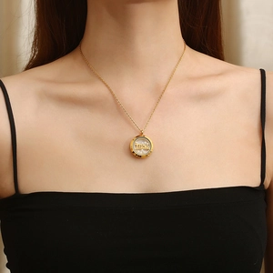 Close-up of golden round pendant necklace with Mãe text and small pearls on a model