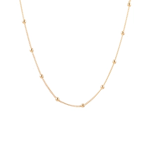 Gros plan d'un collier délicat plaqué or avec de petites perles rondes et élégantes
