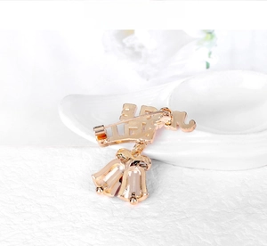 Macro shot of rose gold Chinese Wang character brooch with lucky bells on white background