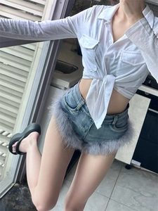 Detail von blauen Jeans-Shorts mit grauem Federbesatz und weißem Bindegürtel-Hemd