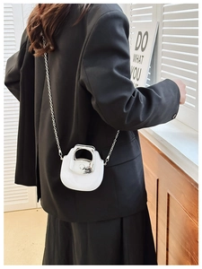 Mini white crossbody bag with silver chain strap shown styled on a black suit jacket