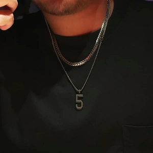 Close-up of men wearing silver Cuban link chain and black necklace with number 5 pendant