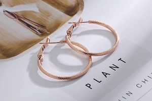 Detailed macro view of rose gold hoop earrings with textured diagonal stripe patterns