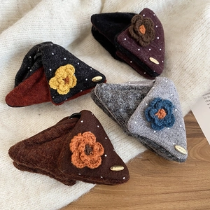 Close-up of four knit flower hair claws in brown, grey, black, and wine red tones