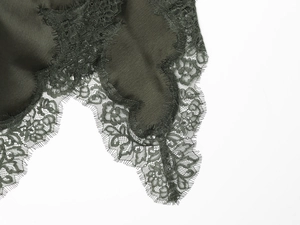 Détail du tissu en soie vert foncé avec bordure en dentelle noire délicate