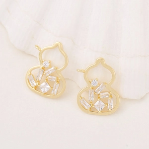 Detail of two golden gourd pendants with clear zircon inlays on white shell background