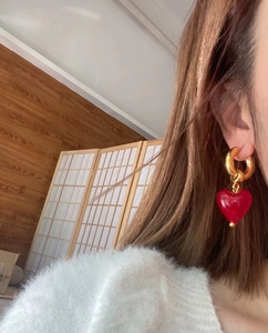 Close-up of a vintage Murano-style red heart earring with a golden hoop on a model