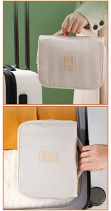 Beige travel toiletry bag with handle shown held and packed inside a white suitcase