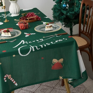 Green Christmas tablecloth with Merry Christmas text and holiday patterns on a festive table