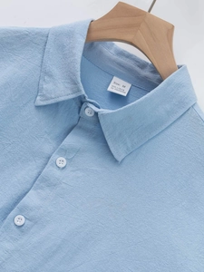 Detailed macro view of the linen blend fabric texture and collar stitching on a men's blue shirt