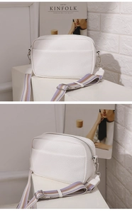 Detail of white litchi pattern PU crossbody bag with colorful striped wide shoulder strap