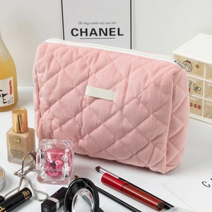 Détail de la trousse de maquillage en velours rose avec motif matelassé et zip blanc