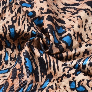 Macro detail of leopard and snake print fabric with blue accents and satin finish
