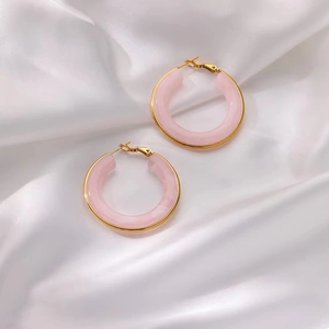 Boucles d'oreilles créoles C en résine rose marbrée avec bordure dorée sur soie blanche