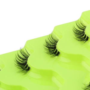 Detailed macro shot of curly half-set false eyelashes on a vibrant neon green tray