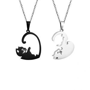 Close-up of black and silver cat necklaces forming a heart shape for couples