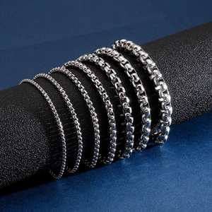 Bracelets gourmette en acier argenté de diverses largeurs sur un présentoir cylindrique noir