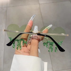 Close-up of heart-shaped green lenses with sparkling crystal drip detail and gold metal frame