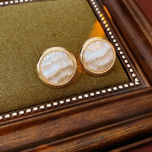 Détail de boucles d'oreilles cœur plaquées or avec incrustation en nacre sur bois