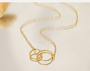 Macro shot of interlocking triple ring gold necklace pendant with subtle texture