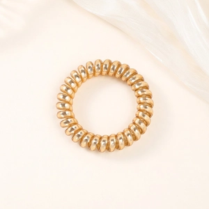 Detail of high-elasticity golden spiral hair coil on white silk fabric background