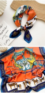 Detailed macro view of silk square scarf with orange horse carriage prints and texture