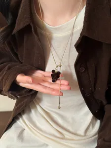 Detailansicht der dunkelbraunen beflockten Trauben-Quaste am goldenen langen Pullover-Halskette