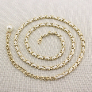 Detail of golden metal chain belt with white leather weave and large pearl pendant charm