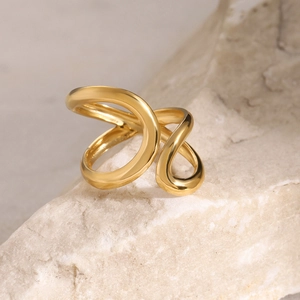Polished gold sculptural wrap ring displayed on natural textured stone background