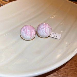 Vue détaillée de boucles d'oreilles boules à motif marbré rose et blanc sur un plat