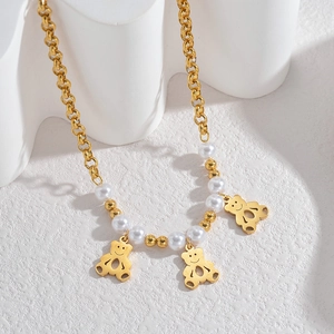 Vue détaillée du collier de perles avec pendentifs ours dorés et motifs cœur ajourés