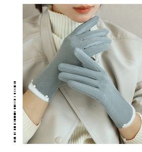 Detail von grauen Wildlederhandschuhen mit weißem Pelzbesatz und eleganten Perlenverzierungen