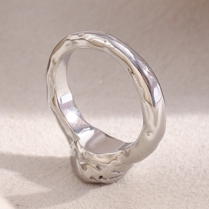Macro detail of silver-colored ring featuring a raw molten lava texture and polished inner