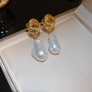 Close-up of vintage baroque pearl earrings with gold-plated knot hooks in a jewelry box