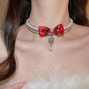 Close-up of elegant double-layer choker with red fabric bow and pearl floral pendant