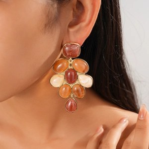 Macro detail of retro resin geometric dangle earrings with marble texture in gold frames