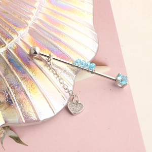 Macro detail of a silver industrial barbell featuring blue gems and a sparkling heart charm