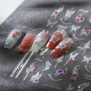 Macro shot of 5D embossed nail stickers featuring rose and butterfly patterns on long nails